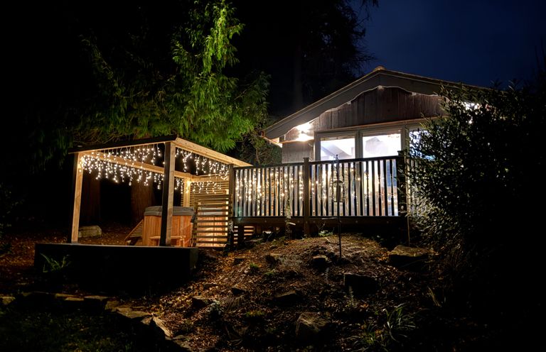 A cabin with a wooden deck and string lights at night at Sir George Baker Cabin in Uplyme