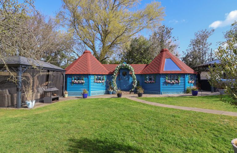 A blue cottage with a red roof and garden at Applejacks Orchard in Holywell