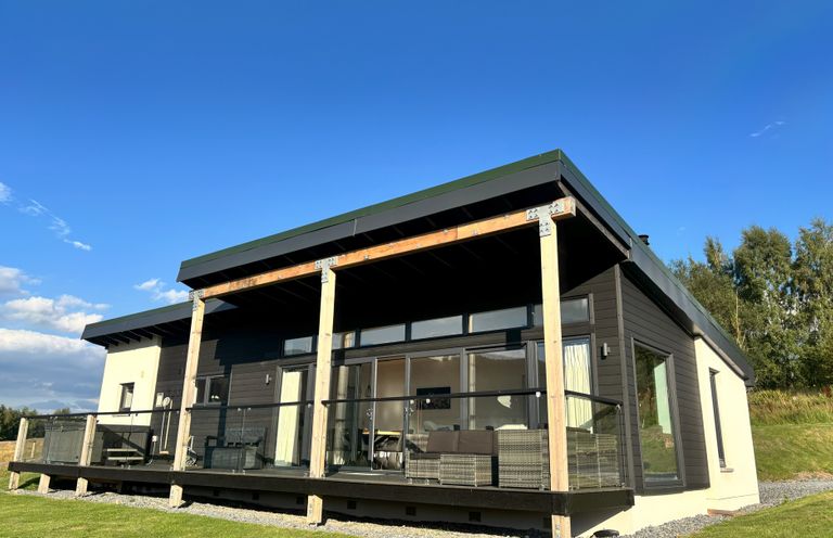 A house with a deck and glass railing at Osprey View Lodge & Hot Tub Aberfeldy
