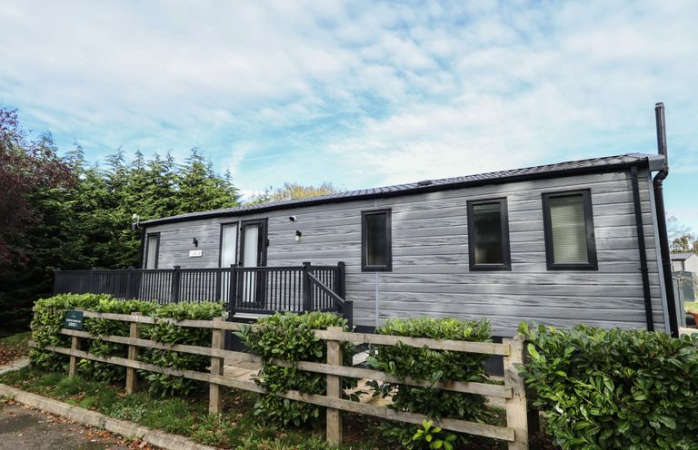 A house with a deck and fence at Heather William Lodge near Woodhall Spa