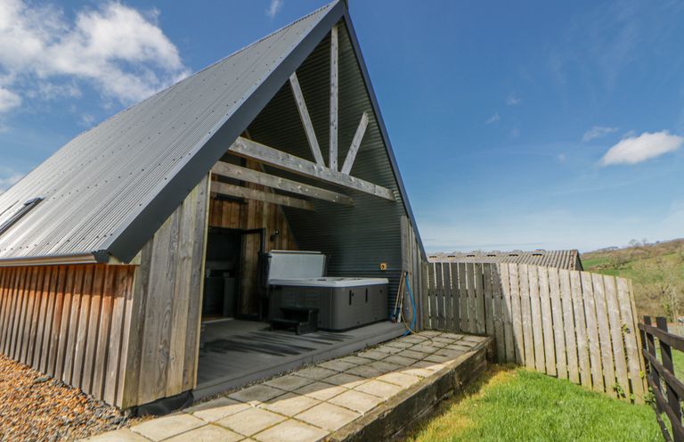 An outdoor area with a hot tub and wooden fences at Valley View Hideaway in Ffostrasol