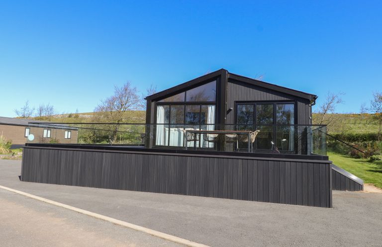 A house with a deck and glass railing at Encil Gyfrinfa in Gwynus, near Llithfaen