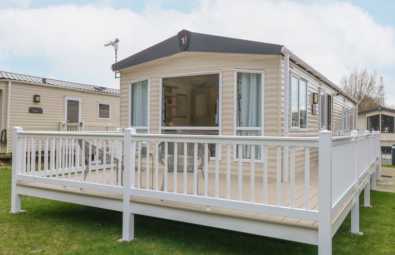 A mobile home with a white fenced deck and outdoor chairs at No 3 Foxburrow Hang in Belton