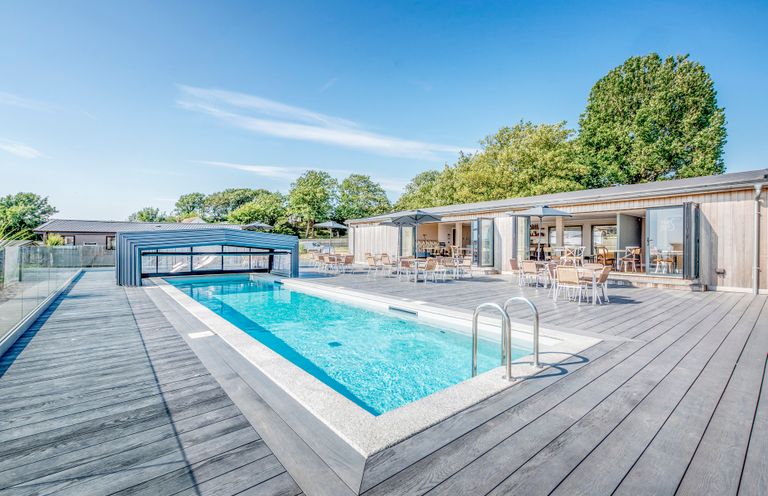 An outdoor area with a swimming pool and seating at Chalet 7 at Landscove Holiday Park Brixham