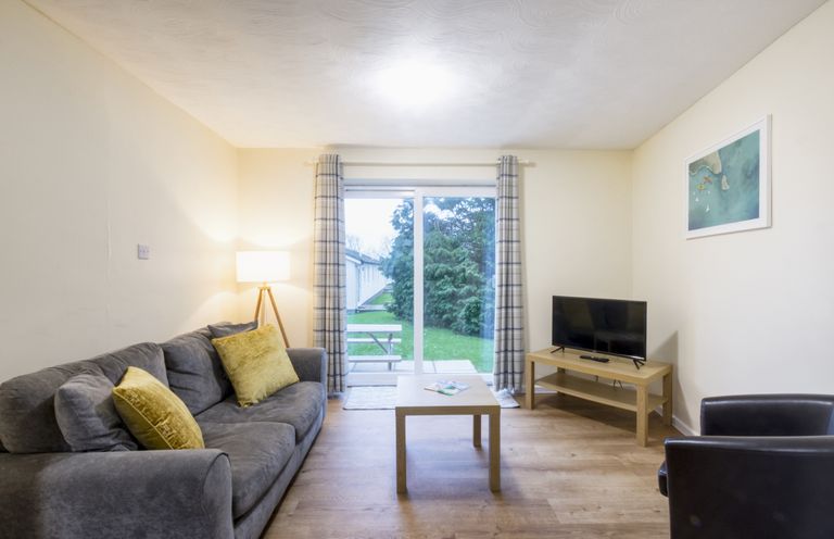 A living room with a sofa and television at Chalet 11 at Landscove Holiday Park in Brixham