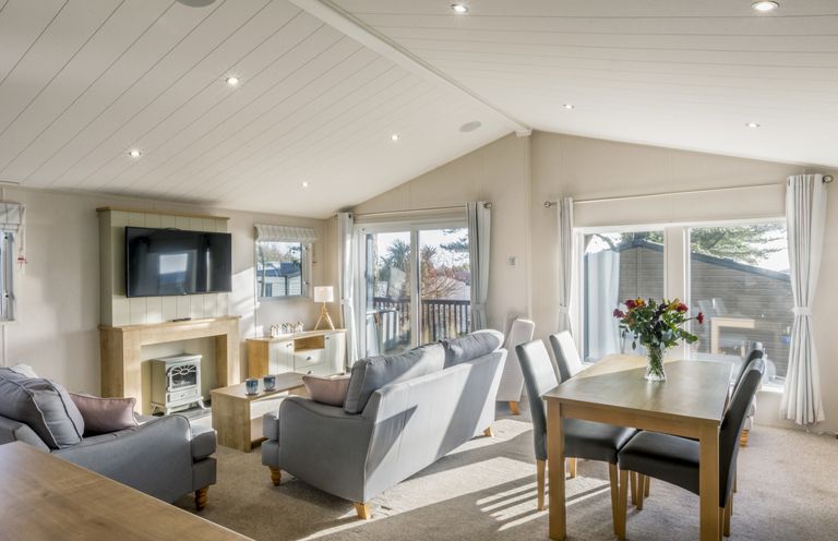 A living room with a sofa and dining table at Lodge 9 at Landscove Holiday Park Brixham