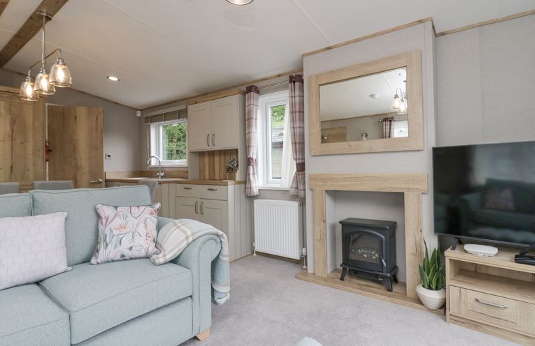 A living room with a light blue sofa and cushions a fireplace and a television at Mon in Troutbeck Bridge