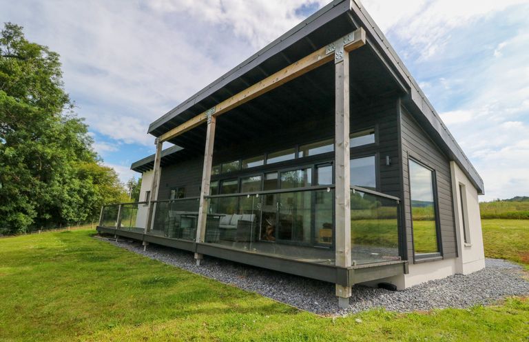 A modern single story house with a glass balcony railing on a grassy lawn at 6 Strathtay Lodges in Aberfeldy