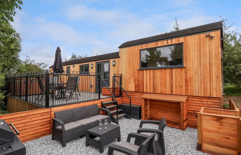 An outdoor patio area with black metal furniture and a wooden building at The View in Bangor-On-Dee