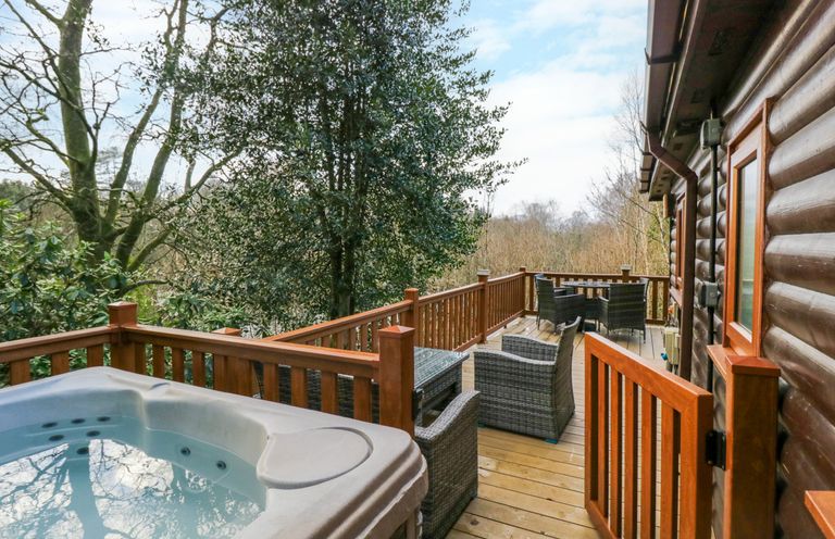 A wooden deck with a hot tub and outdoor seating next to a log cabin at Esk Pike 9 Skiptory Howe White Cross Bay near Windermere