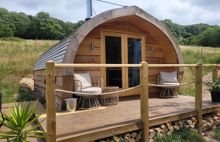 A log cabin with a deck and chairs at Holbein in Matlock