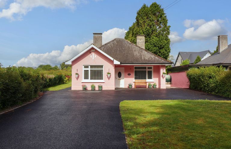 A pink house with a driveway and lawn at Rosemont in Adare