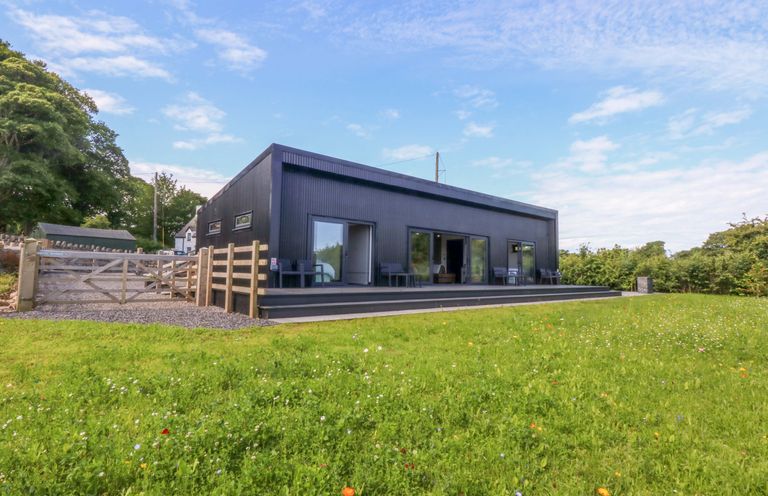 An outdoor view of a house with patio and fence at Y Cwt Moelfre