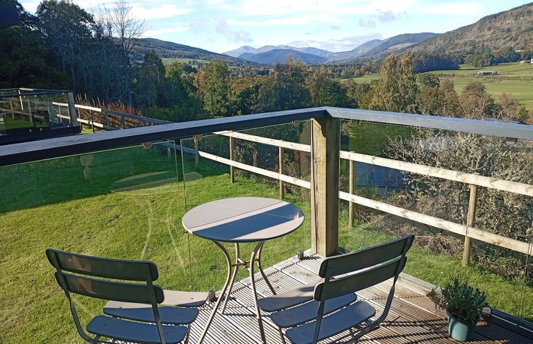 A balcony with a table and chairs overlooking mountains at Dundarach in Aberfeldy