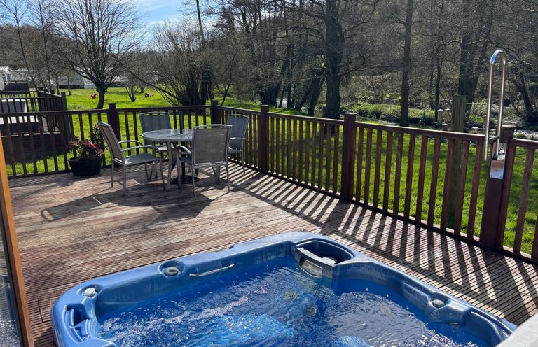 An outdoor area with a hot tub and seating at 2 Riverside Lodge Abercych near Cenarth
