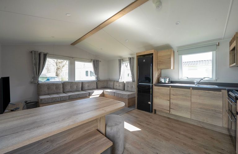 A living room with a sofa and kitchen area at Billy’s Way - Hayling Island