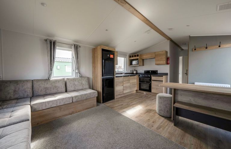 A living room with kitchen appliances and seating area at Sand and Splash - Hayling Island