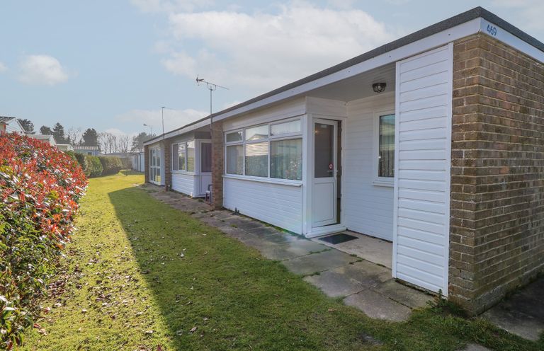 A row of single-story homes with grass and hedges outside at Chalet 469 in Newport Norfolk
