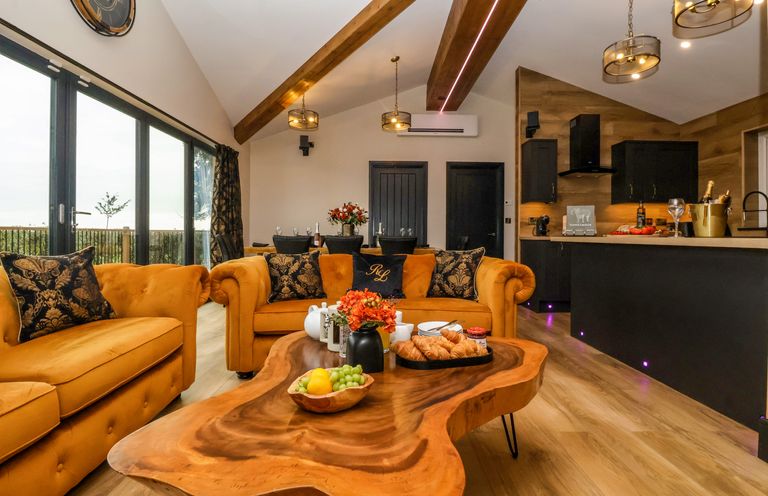 A living room with orange sofas and wooden coffee table next to a kitchen and dining area at Routhorpe Lodge Bainton near Great Driffield