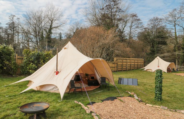 Two bell tents set up on grass with chairs a fire pit and solar panels at Bell tent 3 Camerton near Timsbury