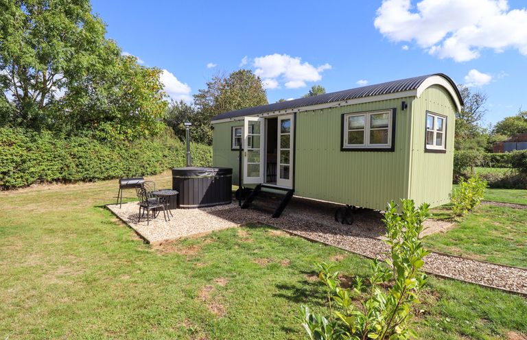 A shepherd hut with hot tub and outdoor seating at Snowdrop in Grimsby