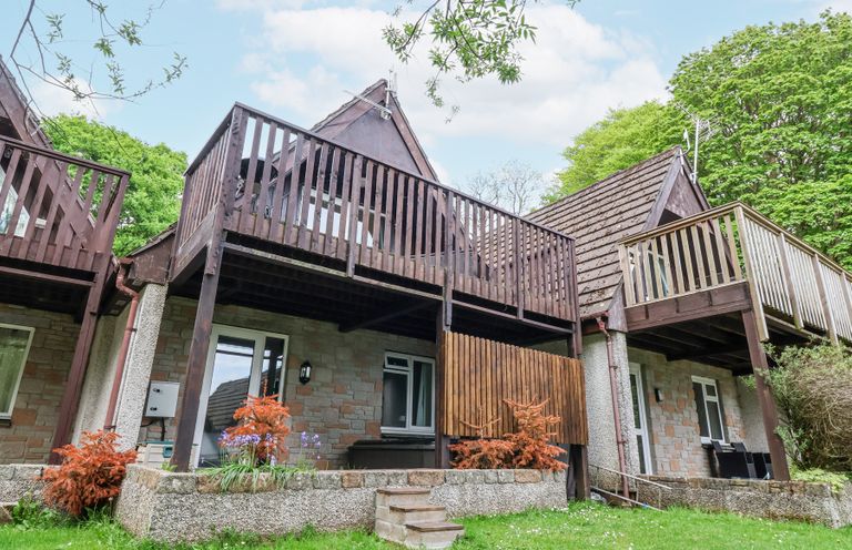 Exterior view of a house with wooden balconies and a grassy lawn at 23 Valley Lodge in Gunnislake