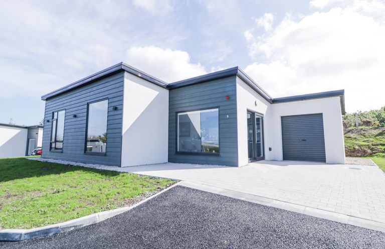 A modern single-story house with dark paneling and white walls with a driveway and garage at Number 5 Villa - The View in Derrybeg County Donegal