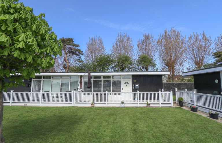 A single story house with white fencing and green grass in front at 99 Cherry Park in Chapel St Leonards