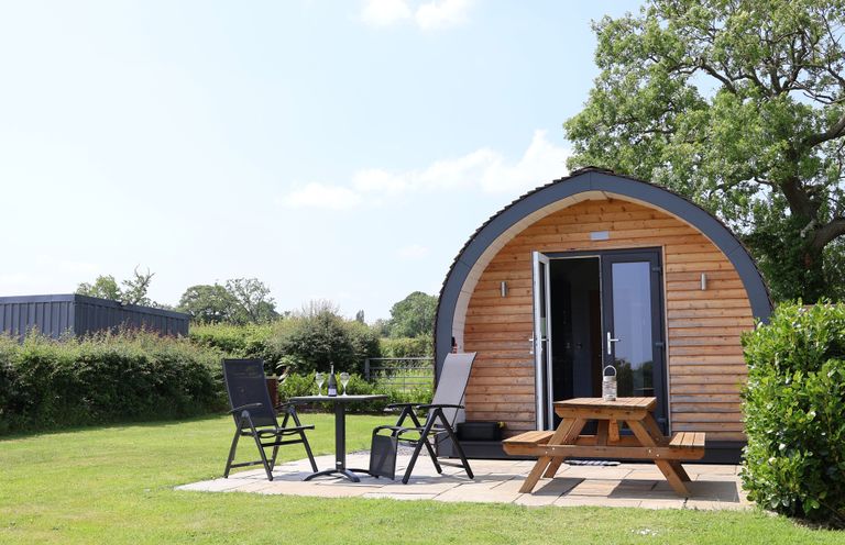 A wooden cabin with a table and chairs at Honeypot Hideaways - Acacia
