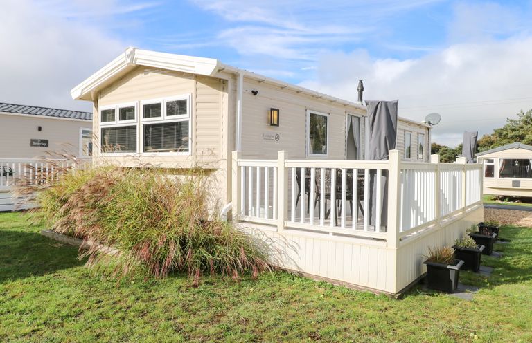 A mobile home with a deck and plants outside Number 34 Foxburrow Hang in Great Yarmouth