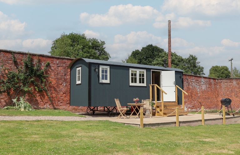 A shepherd's hut with outdoor seating area at Shepherd's Hut in Wrexham