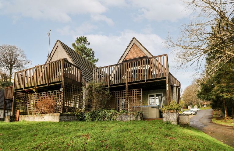 Two adjacent wooden lodges with balconies and a grassy area in front at Valley Lodge 31 in St Ann's Chapel Cornwall