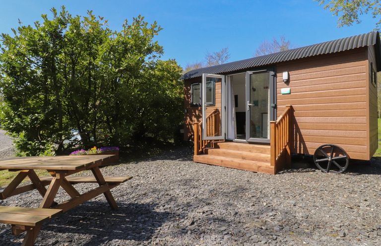 An outdoor view of a cabin with a table and benches at Butterfly Hut 2 Forton near Garstang