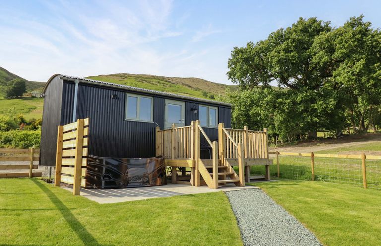 A cabin with a deck and steps in a grassy area at Cheviot in Oswestry