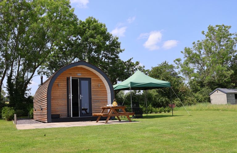 A cabin with a table and tent in an outdoor space at Honeypot Hideaways - Clover