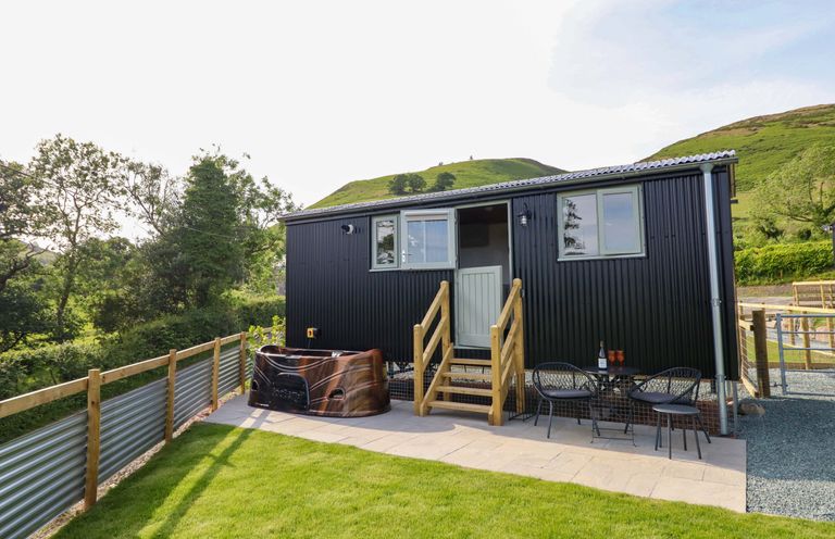 A hot tub and seating area outside a cabin at Charollais in Oswestry