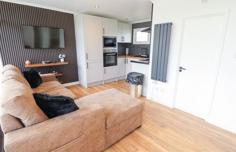 A living room with a sofa and kitchen area at 66 Cherry Park in Skegness
