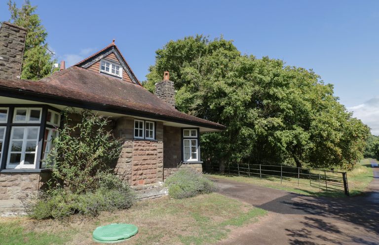 A house with a driveway and trees at Raglan Lodge Monmouth