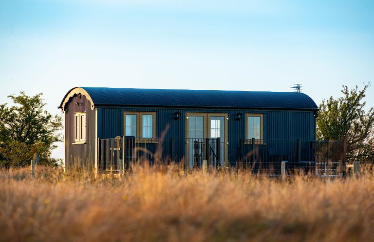A shepherd's hut with windows and a door at Head For the Hills Glamping - Skylark Shepherd's Hut