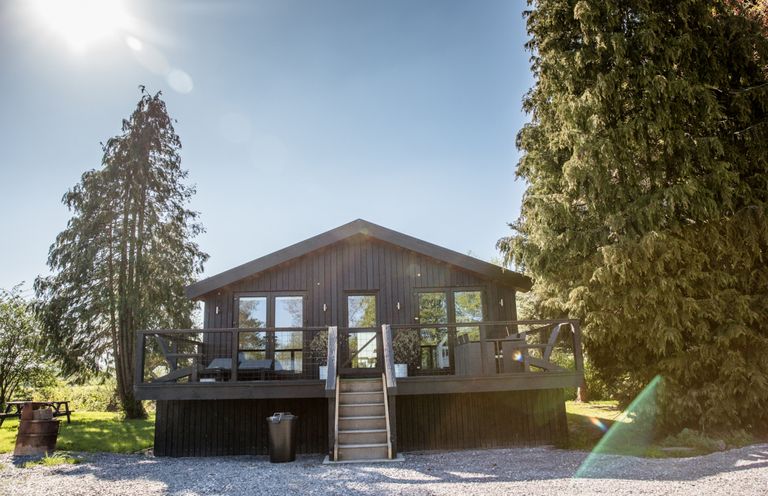 A house with a deck and stairs surrounded by trees at The Larch House in Farndon