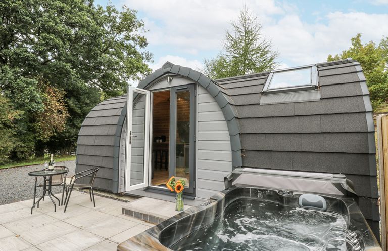 A hot tub and seating area outside a modern structure at Oak View in Rhayader