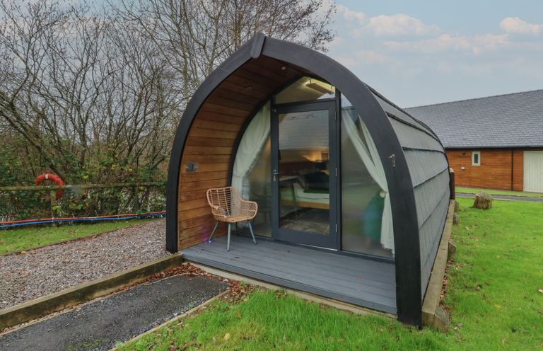 A cabin with a glass door and chair outside at Garden Lodge 1 Swansea