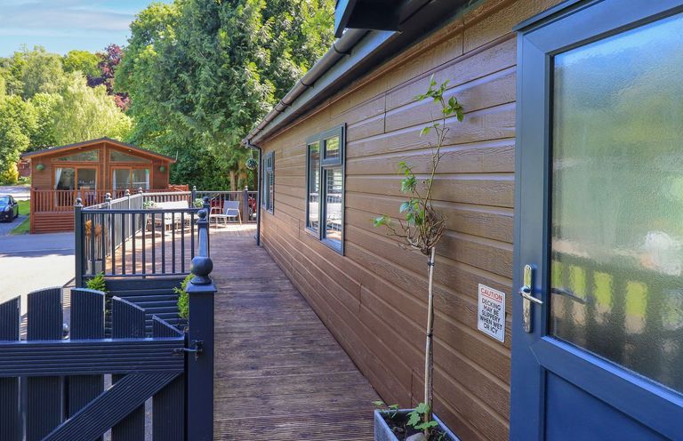 An outdoor view of a wooden house with decking and a planter at Evermore Lodge, 48 Calgarth Park, White Cross Bay, Windermere