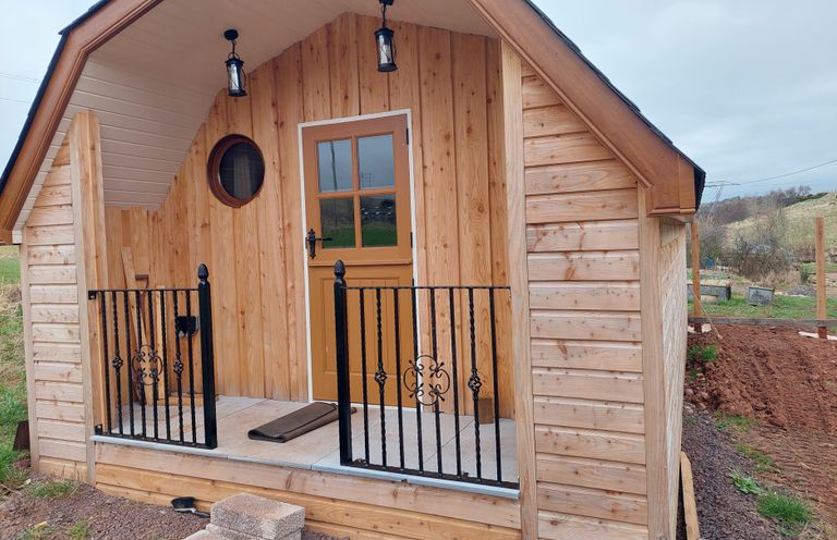 A wooden cabin with a door and railing features at an outdoor location