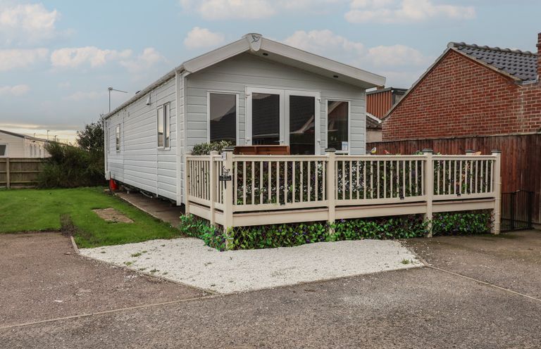 A mobile home with a deck and grass area at Offspray Court 1 in Scratby