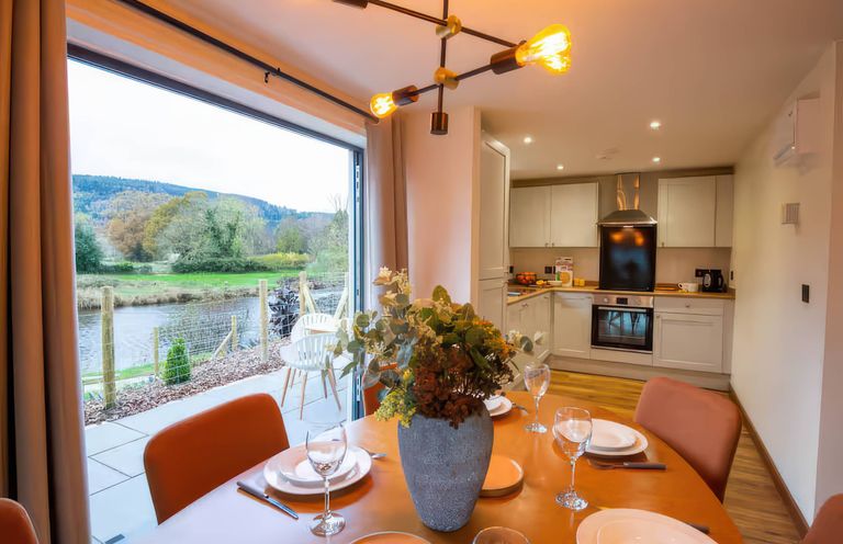 A dining room with a table set near a kitchen at Mountain View Cottage in Llanrwst