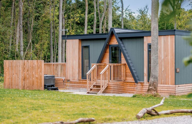 A wooden cabin with stairs and decking in an outdoor area at Tennyson Spa (Pet) Louth