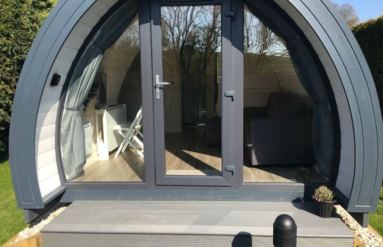 A pod structure with a front door and seating at Pod 1 (Pet Friendly) in Carnforth