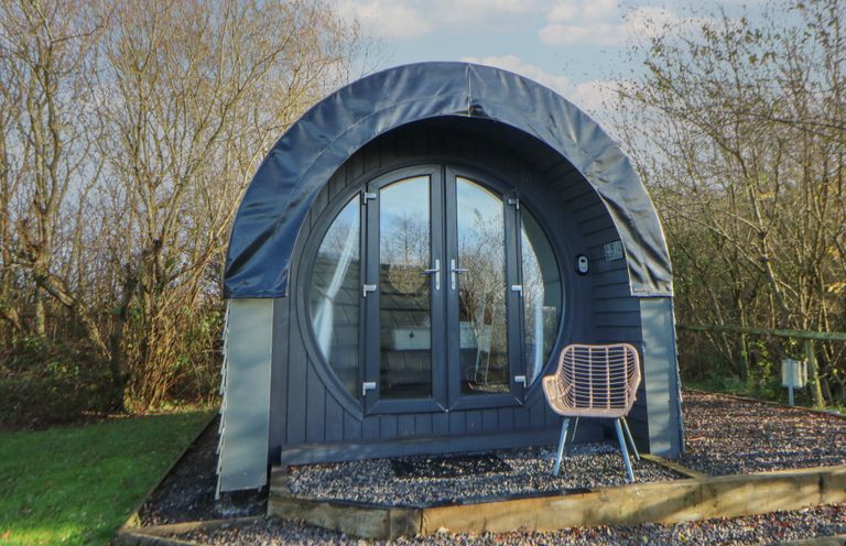 A glamping pod with double doors and a chair at Garden Lodge 5 Swansea