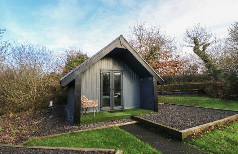 A cabin with a chair and pathway at Garden Lodge 8 in Swansea